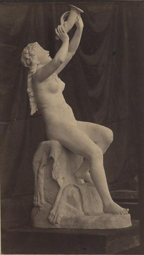 Sculpture : femme nue assise tenant une corne, de profil