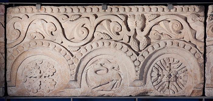 Fragment de frise (04) : Rinceau de vigne avec trois médaillons ornés de feuilles et d'une scène avec un bouc et deux chiens