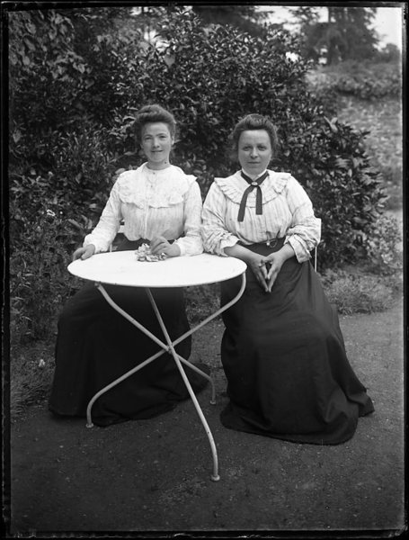 Une jeune fille et la nourrice à une table de jardin
