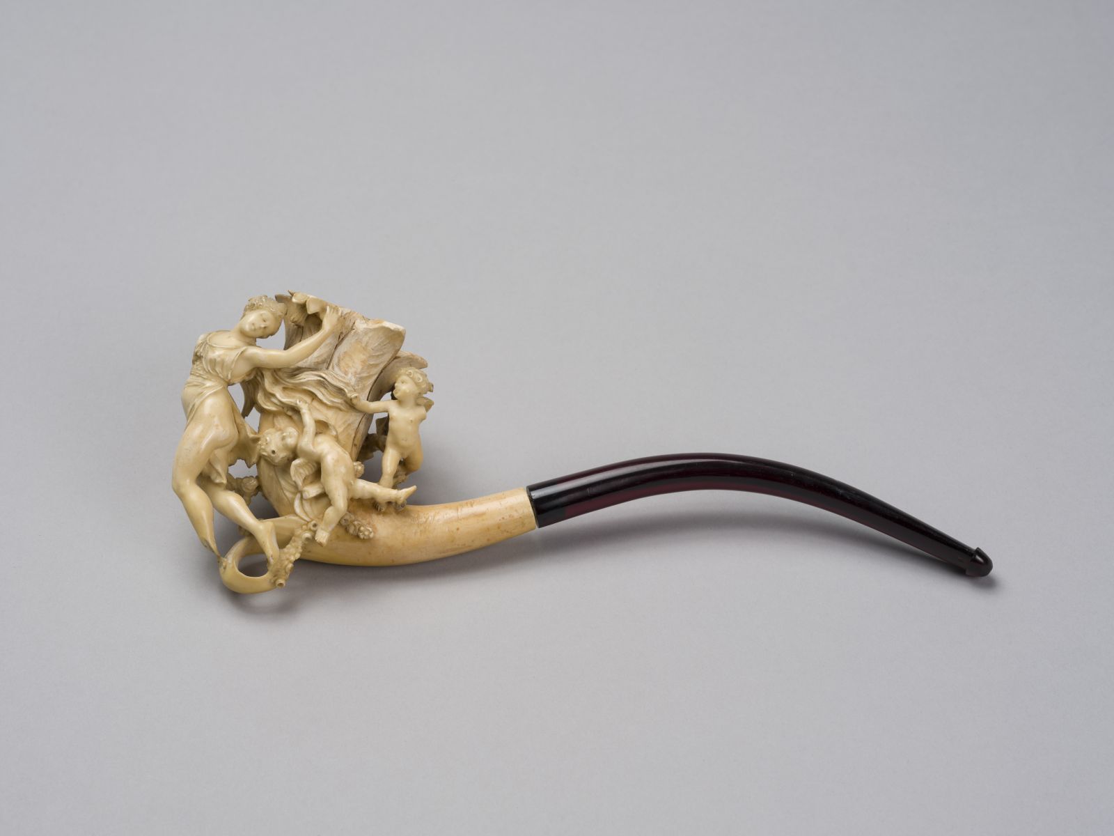 Pipe au fourneau s'évasant en forme de fleur, ornée d'une femme aux longs cheveux auxquels s'accrochent deux amours et deux papillons