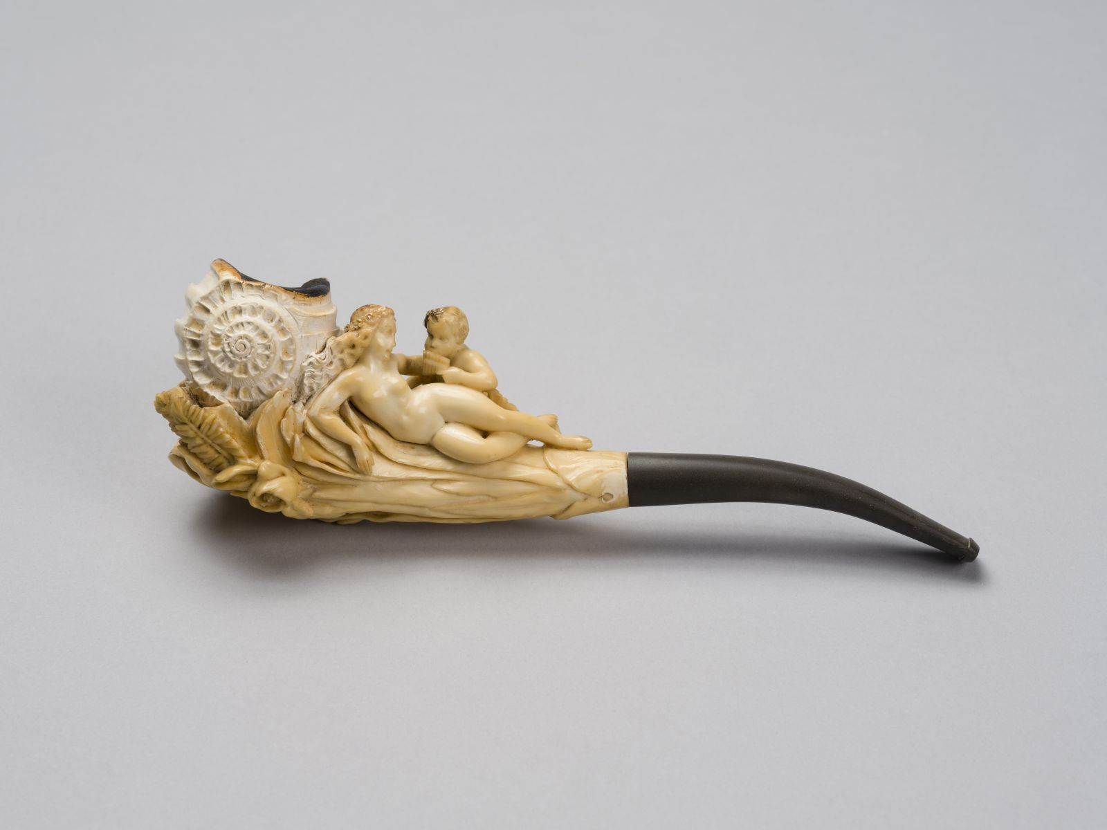 Pipe au fourneau en forme de coquillage émergeant d'un bouquet sur lequel sont installés une naïade et un faune jouant de la flûte de Pan
