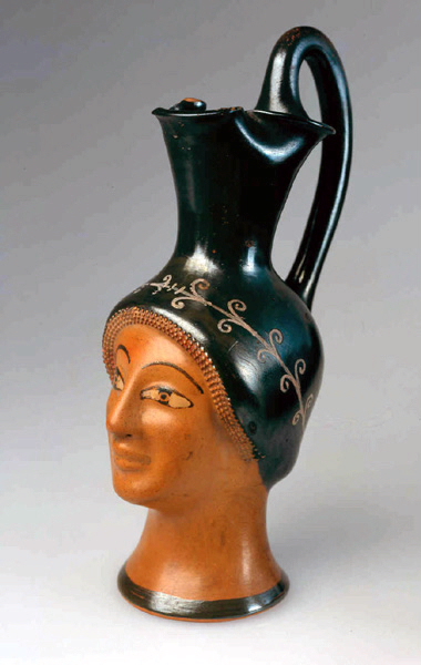 Vase "plastique" ; Oenochoé en forme de tête féminine avec guirlande de fleurs ; Oenochoé plastique à la tête féminine (Titre de la notice de Catherine Lesseur, 2005-2006) ; Oenochoé à embouchure trilobée