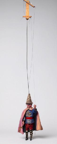 Personnage avec chapeau pointu, cape, bottes et étoile brodée sur le devant de la tunique