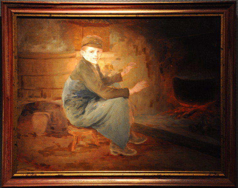 Jeune garçon se réchauffant auprès du feu