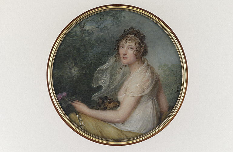 Jeune femme et son chien assis dans un parc tenant des fleurs