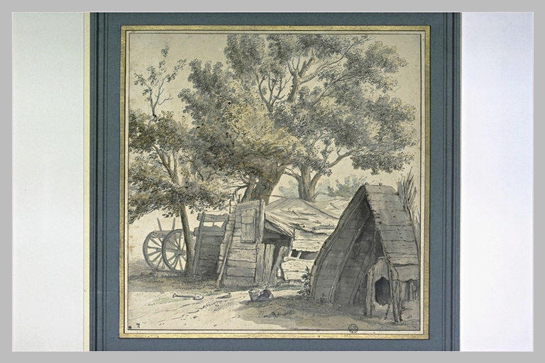 Baraques en bois, à moitié ruinées, sous de grands arbres