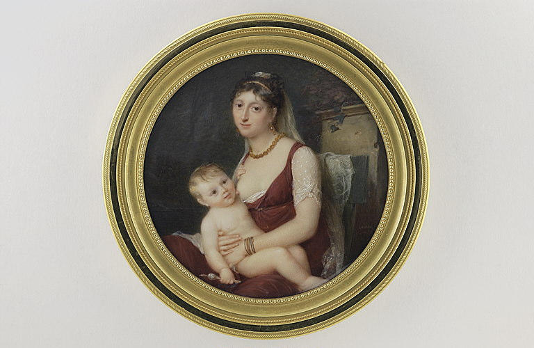 Jeune femme allaitant, assise dans un parc