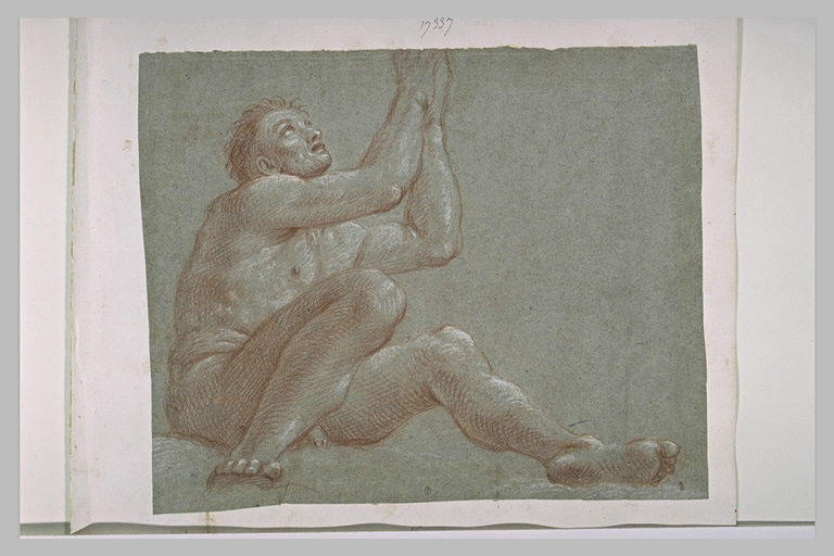 Un homme nu, assis à terre, les yeux et les mains levés au ciel