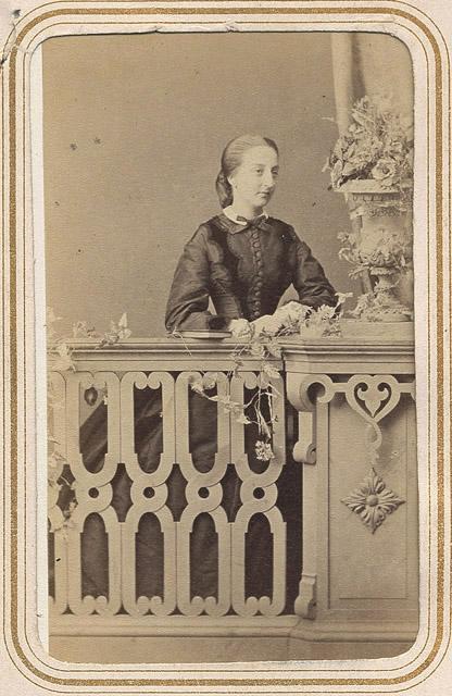 Photographie de femme en noir, derrière une balustrade