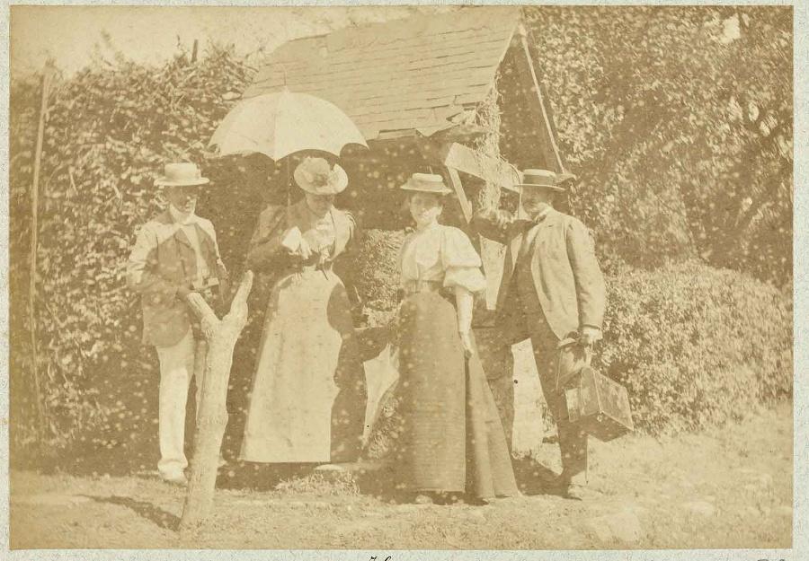 Album de photographies de Chantilly et Saint-Firmin : Deux femmes avec ombrelles et deux hommes debout devant un édifice rural