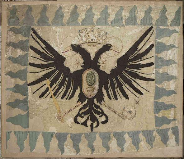Drapeau blanc avec des flammes bleu ciel sur le pourtour et au centre, un aigle à deux têtes noir, pris à Rocroi (?) en mai 1643, encadré sous verre ; Drapeau dit de Rocroi