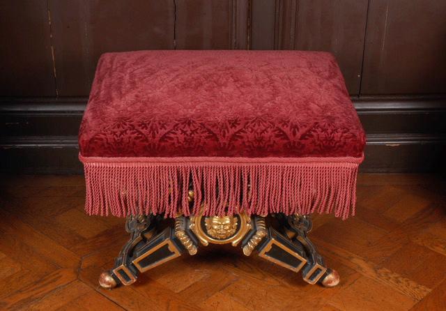 Tabouret à pieds en X en bois peint en noir et doré, recouvert de tissu broché grenat