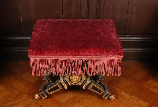 Tabouret à pieds en X en bois peint en noir et doré, recouvert de tissu broché grenat