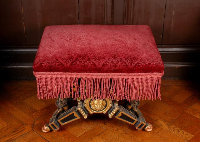 Tabouret à pieds en X en bois peint en noir et doré, recouvert de tissu broché grenat