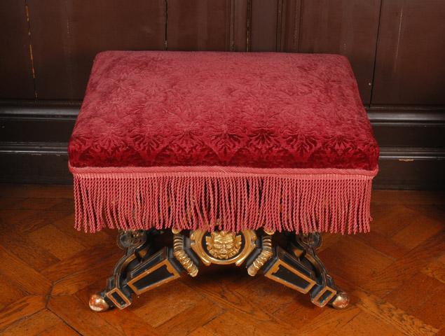 Tabouret à pieds en X en bois peint en noir et doré, recouvert de tissu broché grenat