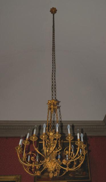 Lustre en bronze doré à 18 feux avec au centre des amours soufflant dans des trompettes et adossé à un flambeau