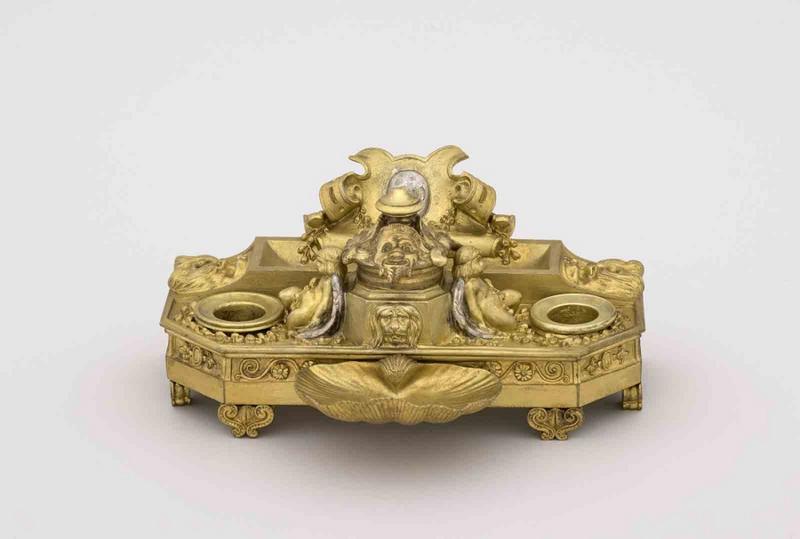Encrier en bronze doré, représentant deux enfants ailés assis de chaque côté de l'encrier central, couvercle décoré de trois têtes grimaçantes