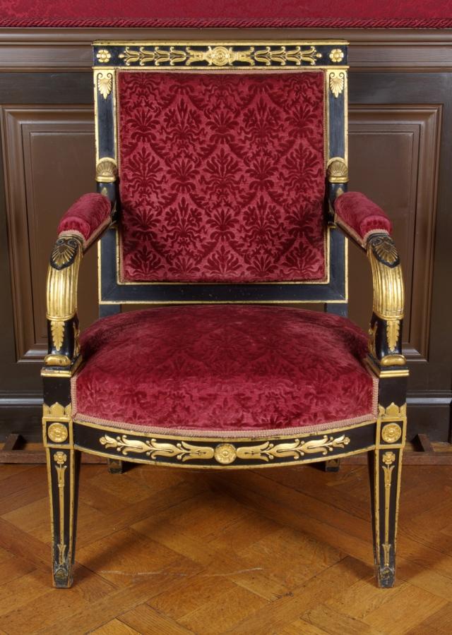 Grand fauteuil à dossier sculpté en bois noir et doré recouvert de velours grenat