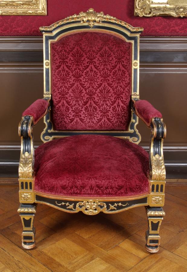 Grand fauteuil à dossier sculpté en bois noir et doré recouvert de velours grenat
