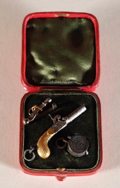 Pistolet miniature à manche doré avec accessoires dans sa boîte en maroquin rouge doublé de soie et de velours vert