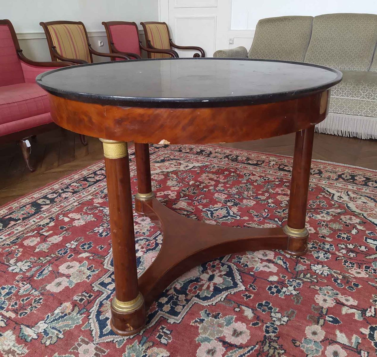 Table ronde recouverte d'un marbre noir,  trois pieds à roulettes