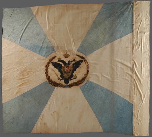 Drapeau blanc avec une croix de Malte bleu ciel, avec un aigle noir à deux têtes couronné au centre et 4 fleurs de lys d’or aux angles