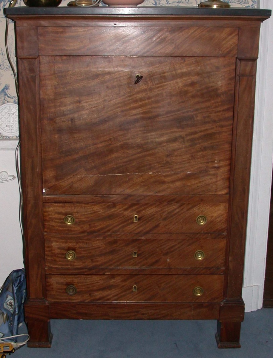 Un secrétaire à abattant, en acajou, recouvert de marbre noir, trois tiroirs avec boutons en bronze doré.