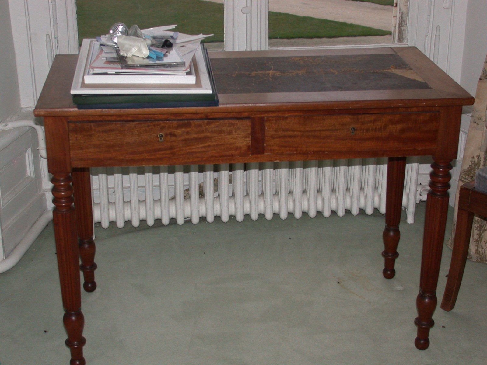 Table en acajou clair recouverte de cuir noir, pieds cannelés et deux tiroirs