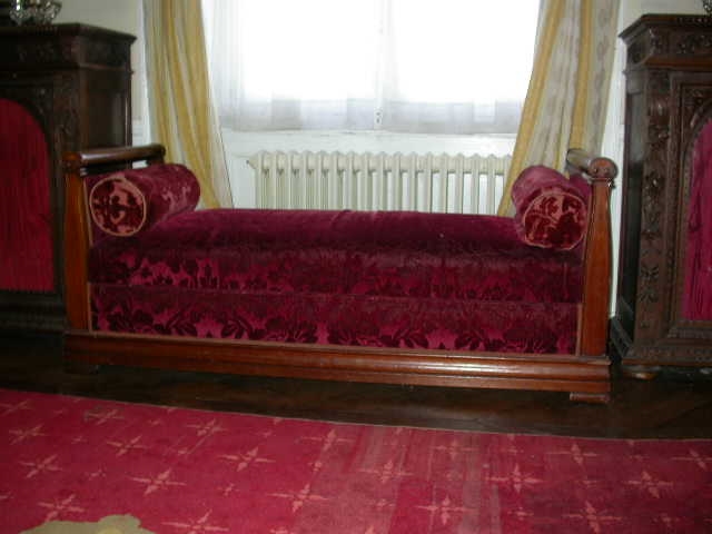 Petit canapé en acajou avec deux accoudoirs à volutes formant coffre, recouvert de velours rouge