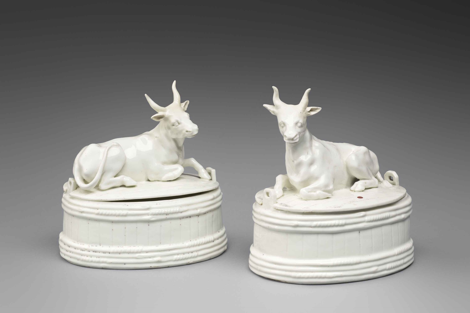 Fromager ou beurrier ovale à couvercle en porcelaine tendre de Chantilly présentant deux barattes de bois ovale et sur le couvercle, une vache couchée émaillé blanc