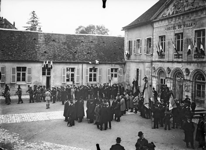 Devant l’Hôtel de Ville, les personnalités, les drapeaux, la fanfare militaire attendant ceux qui sont fêtés (titre usuel)