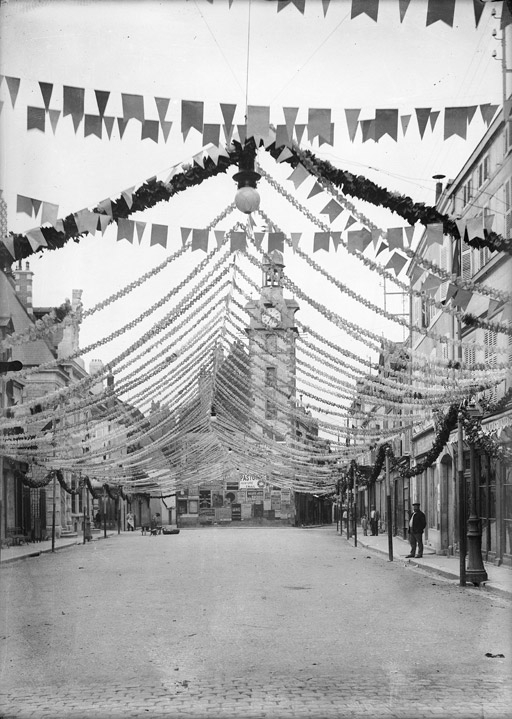 Grand rue (place de la République) décorée de banderoles, le beffroi au fond (titre usuel)