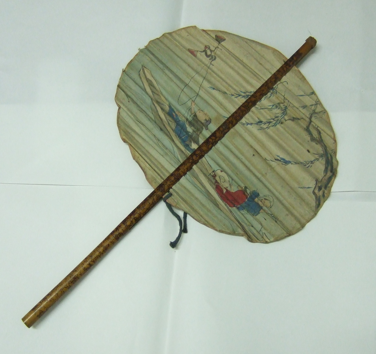 Eventail japonais rond avec un décor de trois personnages dans une barque et un singe. (titre factice)