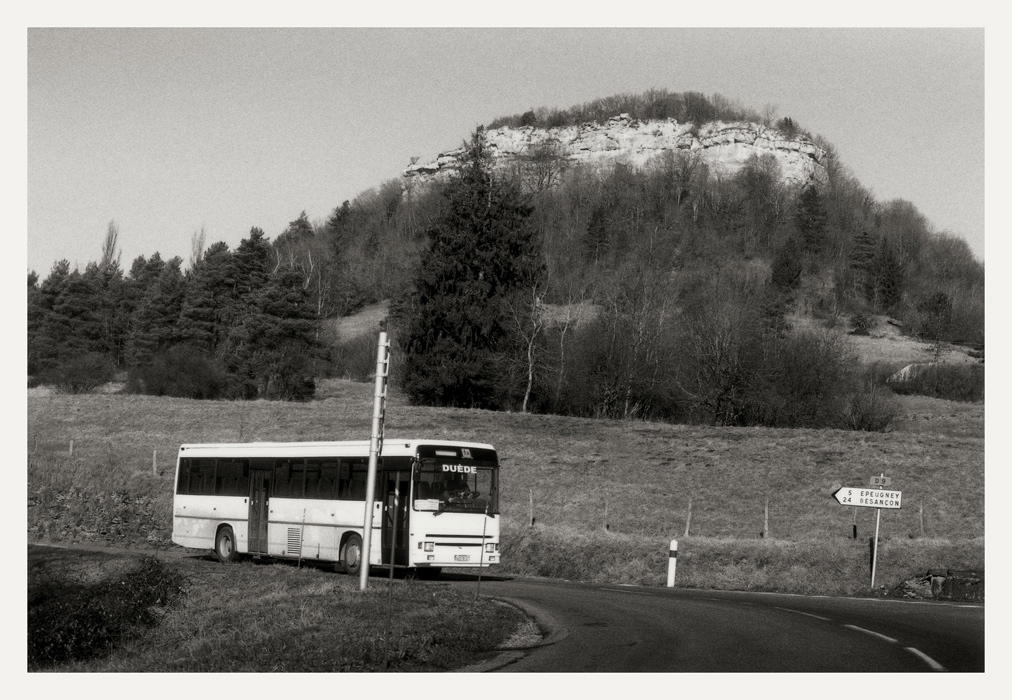Aux environs d'Ornans, 2008, route et autocar avec en arrière-plan un versant boisé et banc rocheux
