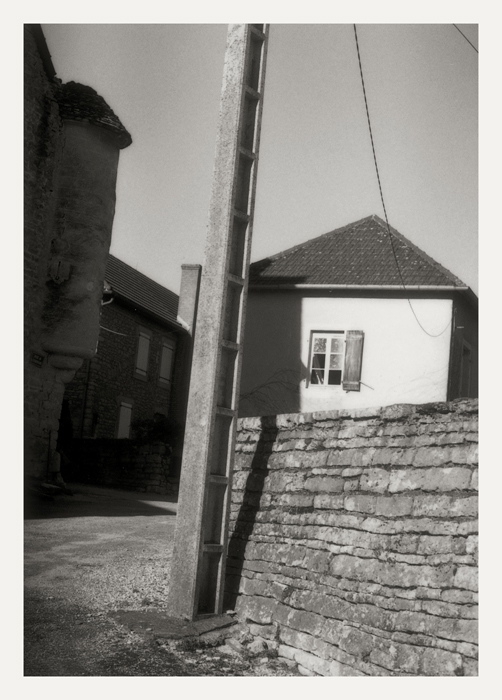 Poteau en ciment, mur de pierres et pignon d'une maisson sur la droite, 2008