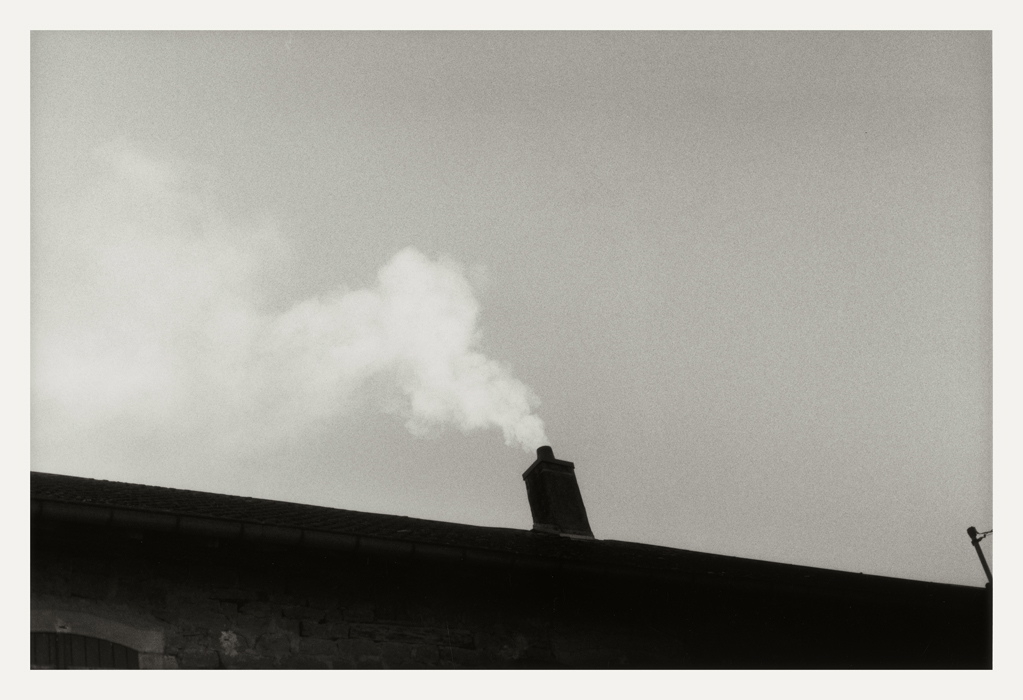 Près de Besançon 2008, vue di sotto in sù montrant un long toit, une cheminée et sa fumée blanche