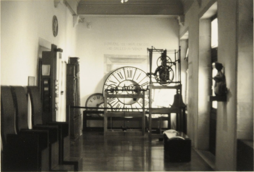 Musée du Temps 2008, premier étage : vue proche de la photo 2013.1.112 mais prise avec plus de recul. Dans le fond de la galerie, grands cadrans d'horloges ; sur la gauche, horloges de parquet ; sur la droite, un mécanisme d'horloge d'édifice et la petite sirène en bronze de Lullier
