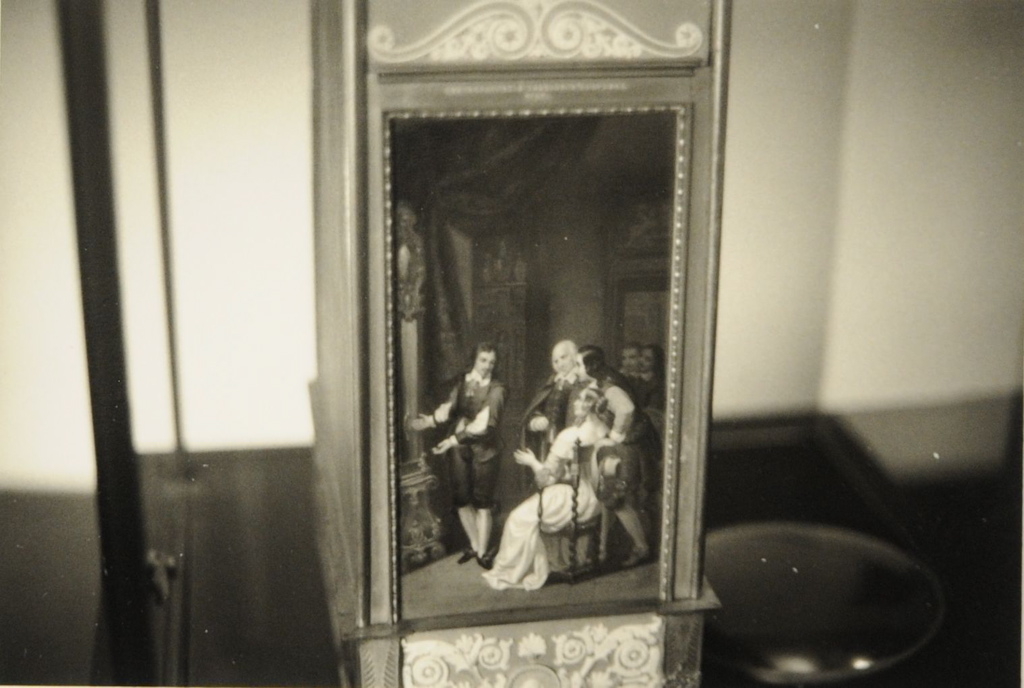 Musée du Temps 2008, gros plan sur une pièce d'horlogerie (cartel ?) ornée d'une petite peinture montrant un groupe de clients dans  une boutique d'horloger