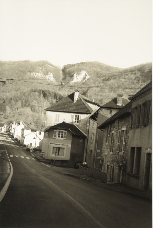 Hautepierre-le-Châtelet 2008, vue d'une rue du village. A l'arrière-plan, versants boisés et bancs rocheux