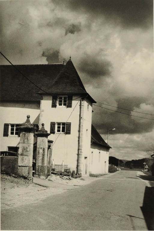 Onoz 2009, à gauche, au bord de la route, maison blanche avec portail de pierre. Ciel assez sombre et nuageux