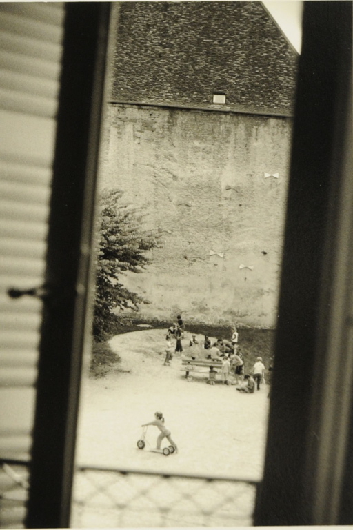 Arbois 2008. A travers une fenêtre, vue plongeante donnant sur une cour où des enfants sont occupés à jouer