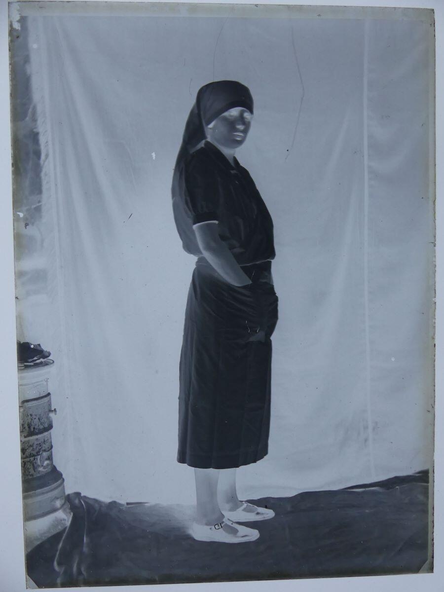 Jeune infirmière, vue en pied, les mains dans les poches de son tablier