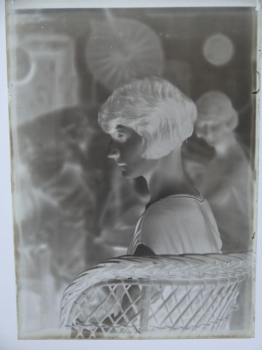 Jeune femme de profil (Andrée Cognard ?), assise dans un fauteuil en rotin, posant dans l'atelier de l'artiste