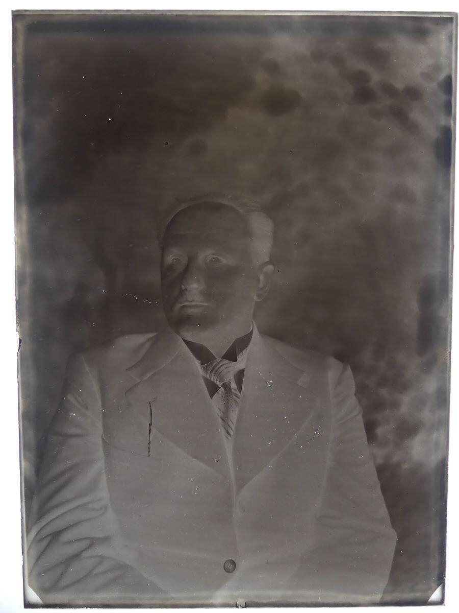 Portrait d'homme, vue en buste, front dégarni, yeux clairs, posant dans un jardin