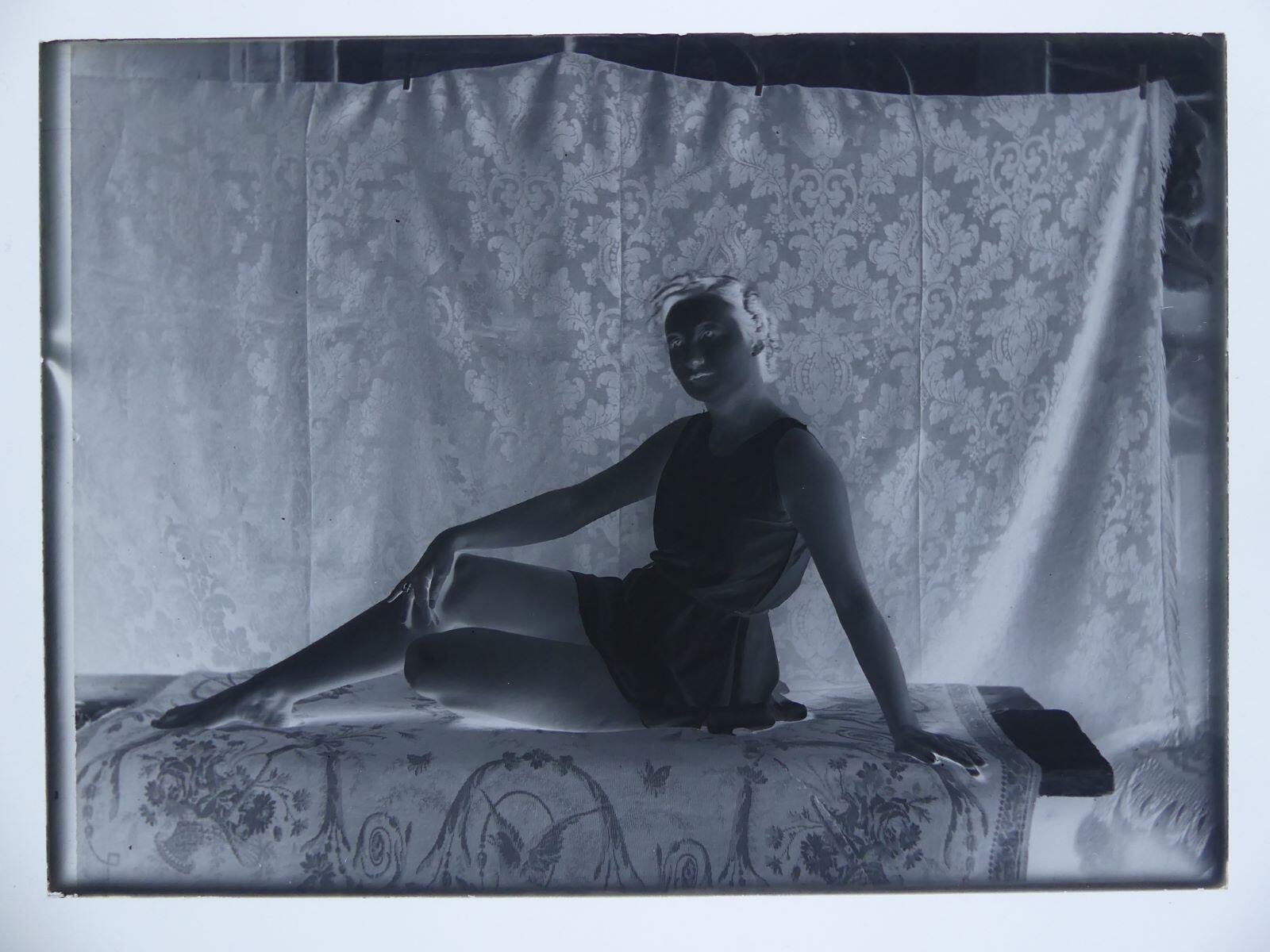 Modèle féminin posant dans l'atelier, assise, appuyée sur son bras droit, la main gauche posée sur son genou