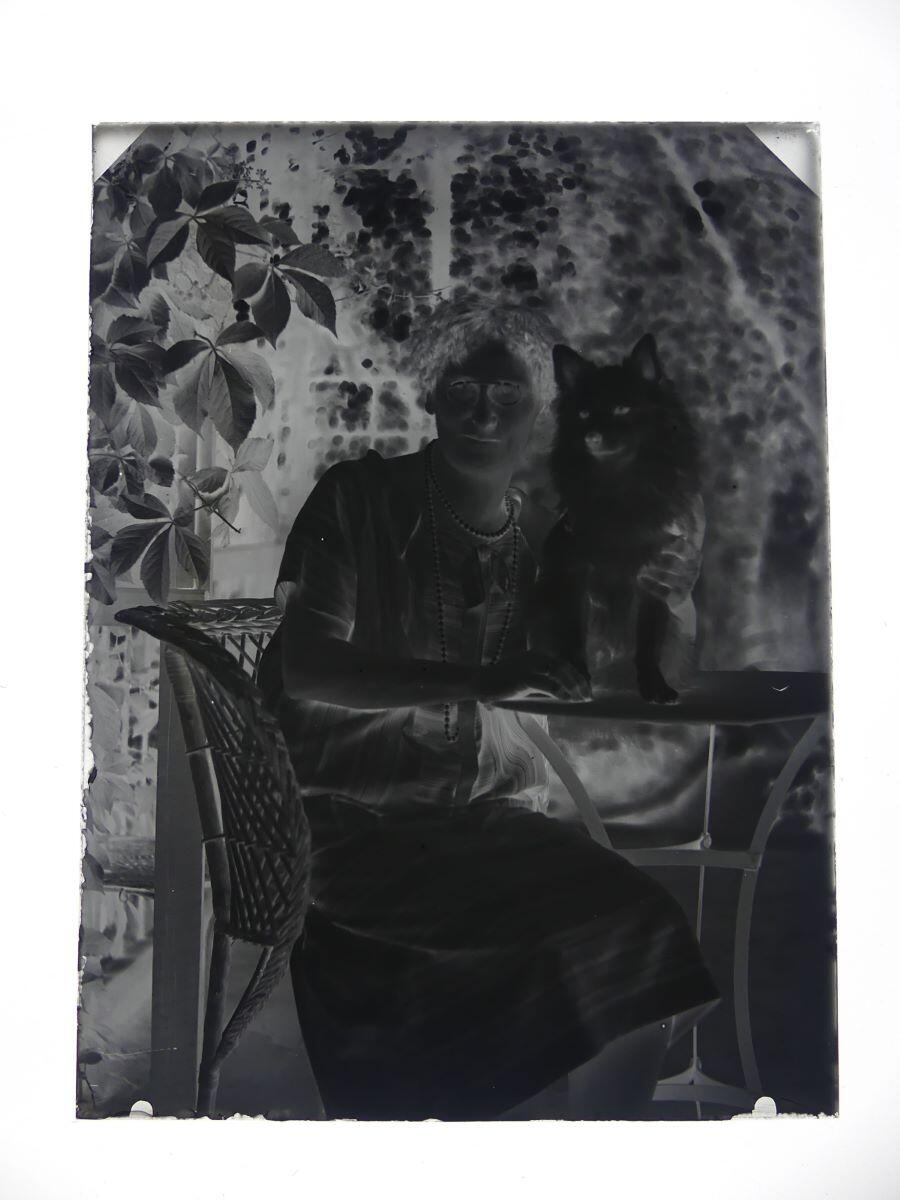 Portrait d'une femme et de son chien posant dans un fauteuil d'osier au jardin