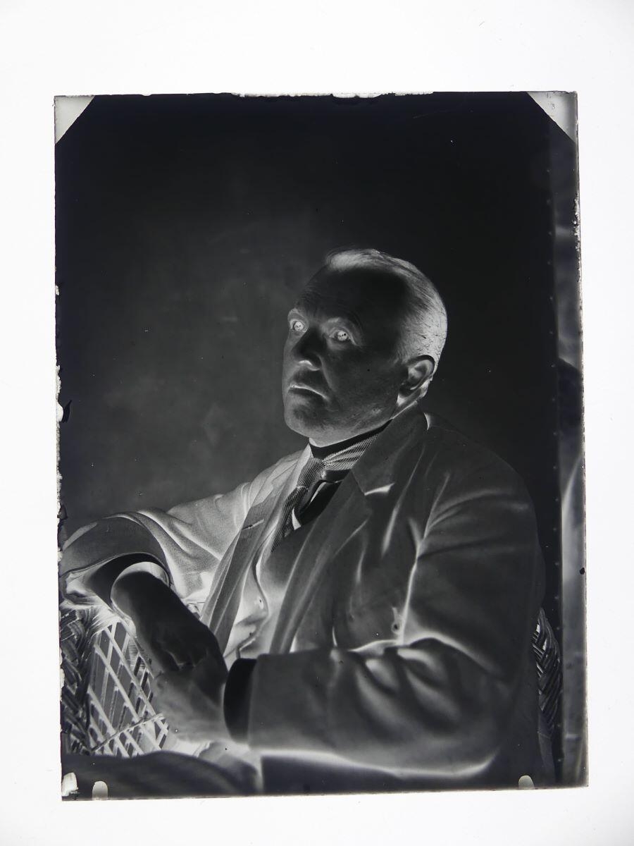 Portrait d'un homme posant de 3/4 droit dans un fauteuil en osier