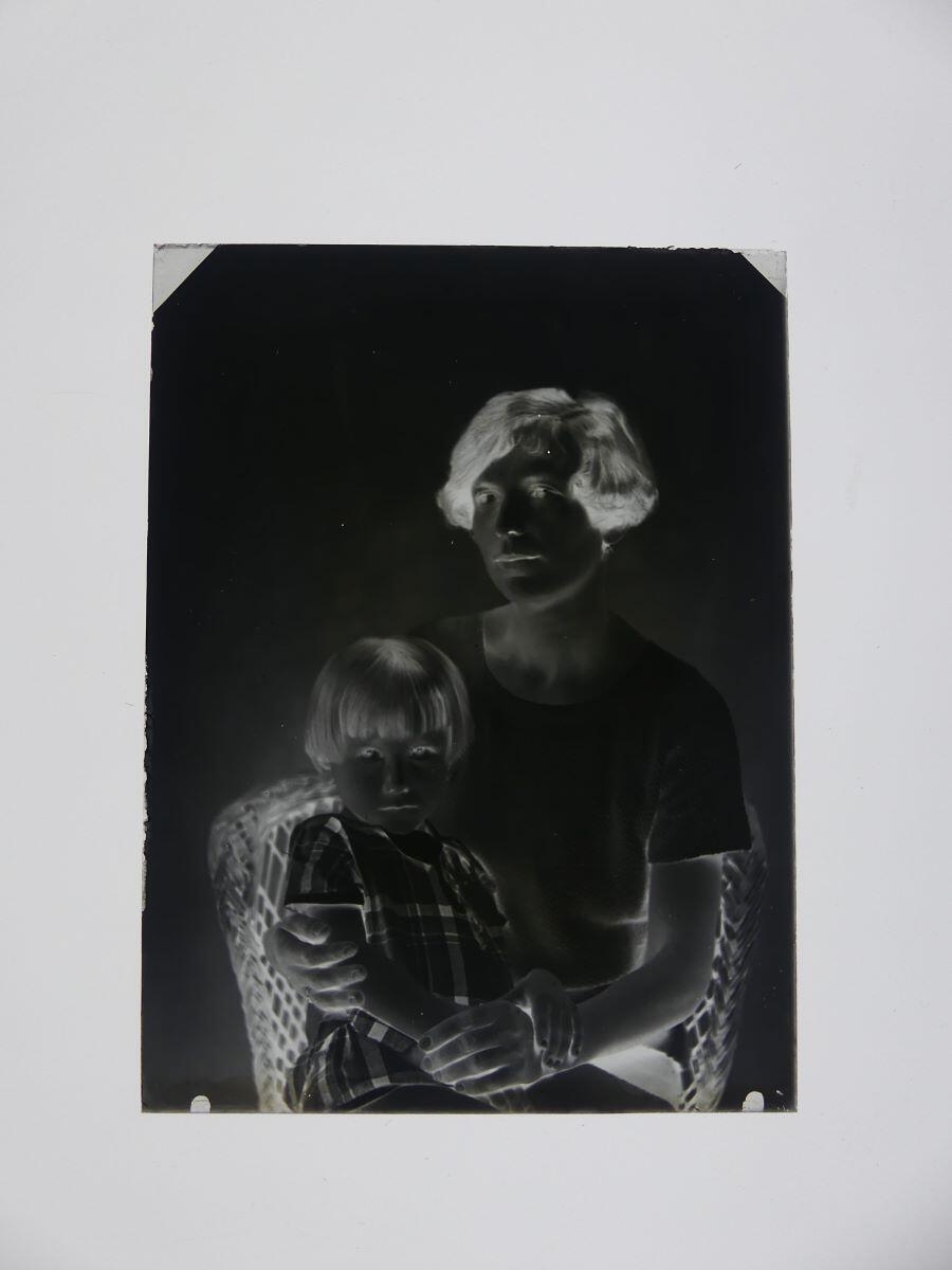 Portrait d'une jeune femme avec une petite fille sur les genoux, posant dans un fauteuil en osier