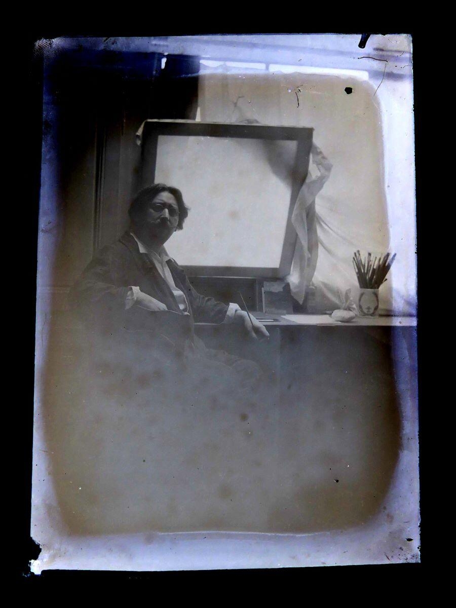 Portrait du peintre Léon Tirode devant une table de travail, assis sur la gauche