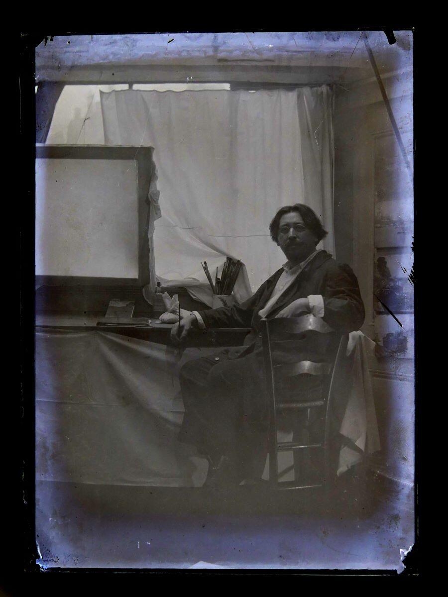 Portrait du peintre Léon Tirode devant une table de travail, assis sur la droite